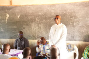 DSC04748 - Tous pour l'homme, chacun pour le faible Smiling man in white robes standing at the front of a classroom teaching several seated men